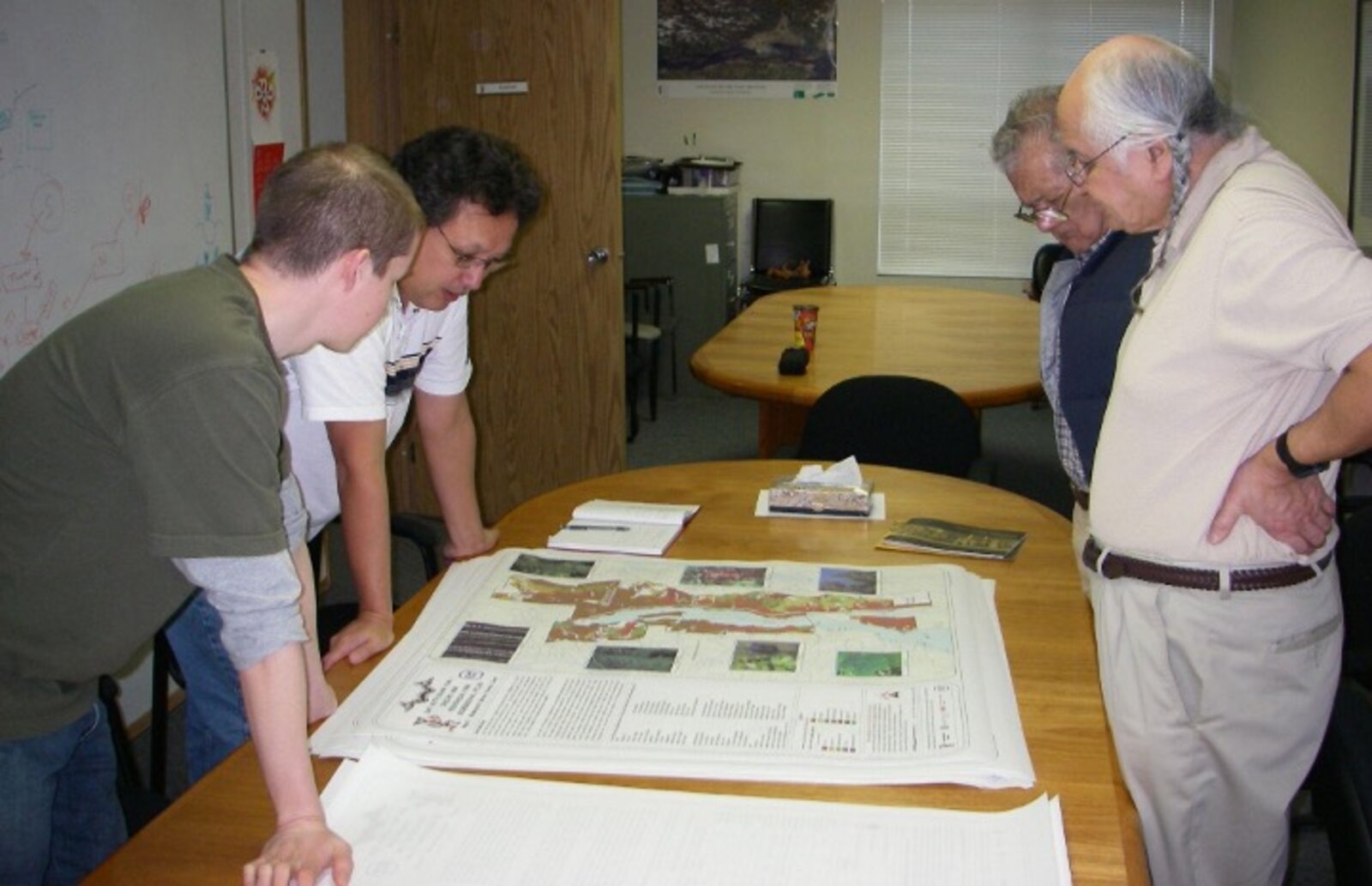 Community members and team reviewing a printed bioregional atlas on a table